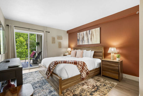Furnished bedroom with a wood bed, matching nightstands, and warm accents